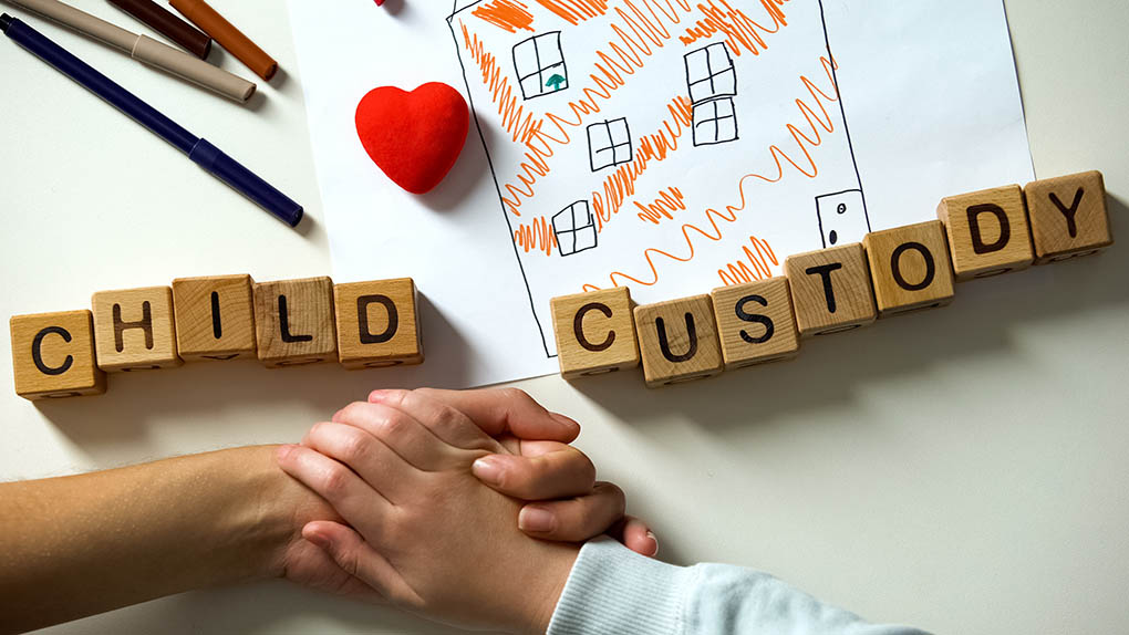 Image of "child custody" spelled out in blocks and a child's hand.